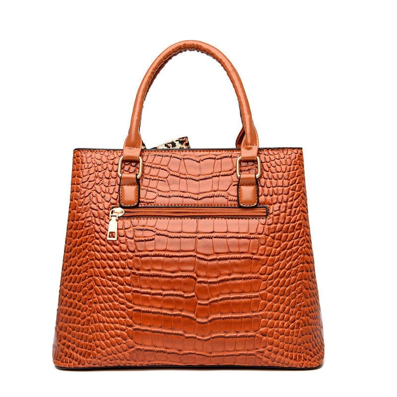Brown leather handbag with crocodile-embossed texture and structured shape.