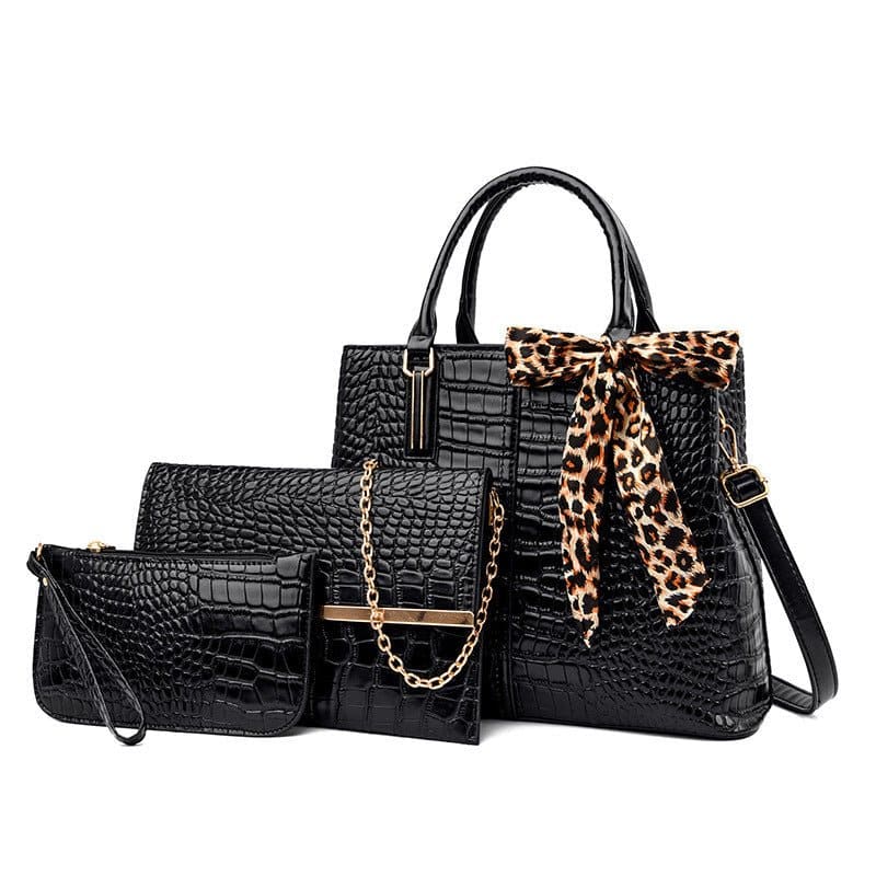 Black crocodile-textured handbag with leopard print scarf accent, accompanied by matching wallet and clutch.