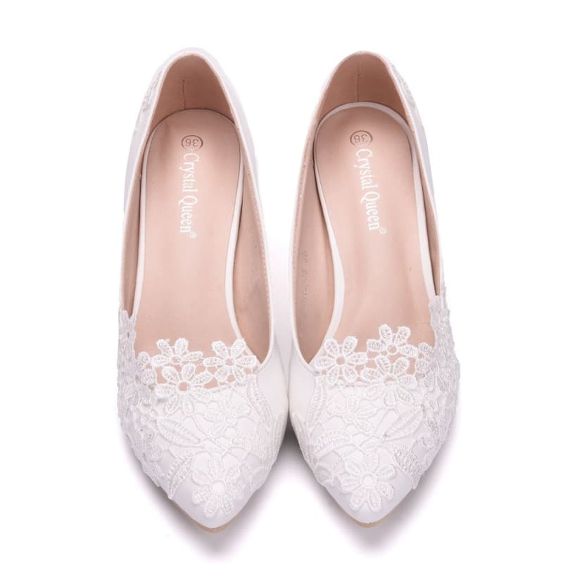 White lace bridal flats with pointed toes and floral embellishments.