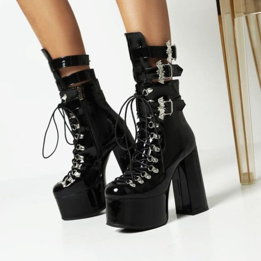 Pair of black platform boots with chunky heels, laces, and buckle straps.
